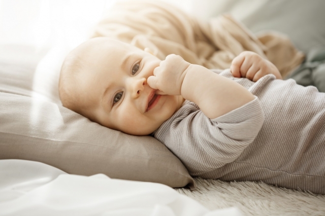 portrait sweet smiling newborn daughter lying cozy bed child looks camera touching face with her little hands childhood moments 3